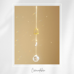 Attrape-soleil artisanal « Mélodie de la Plume » – Cristal pur, oiseau sur balancelle dorée et plume grise